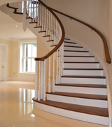 Curved cut string walnut and tulipwood staircase with a continuous and voluted handrail (Blackhill. Private Client. Location: Northern Ireland) 